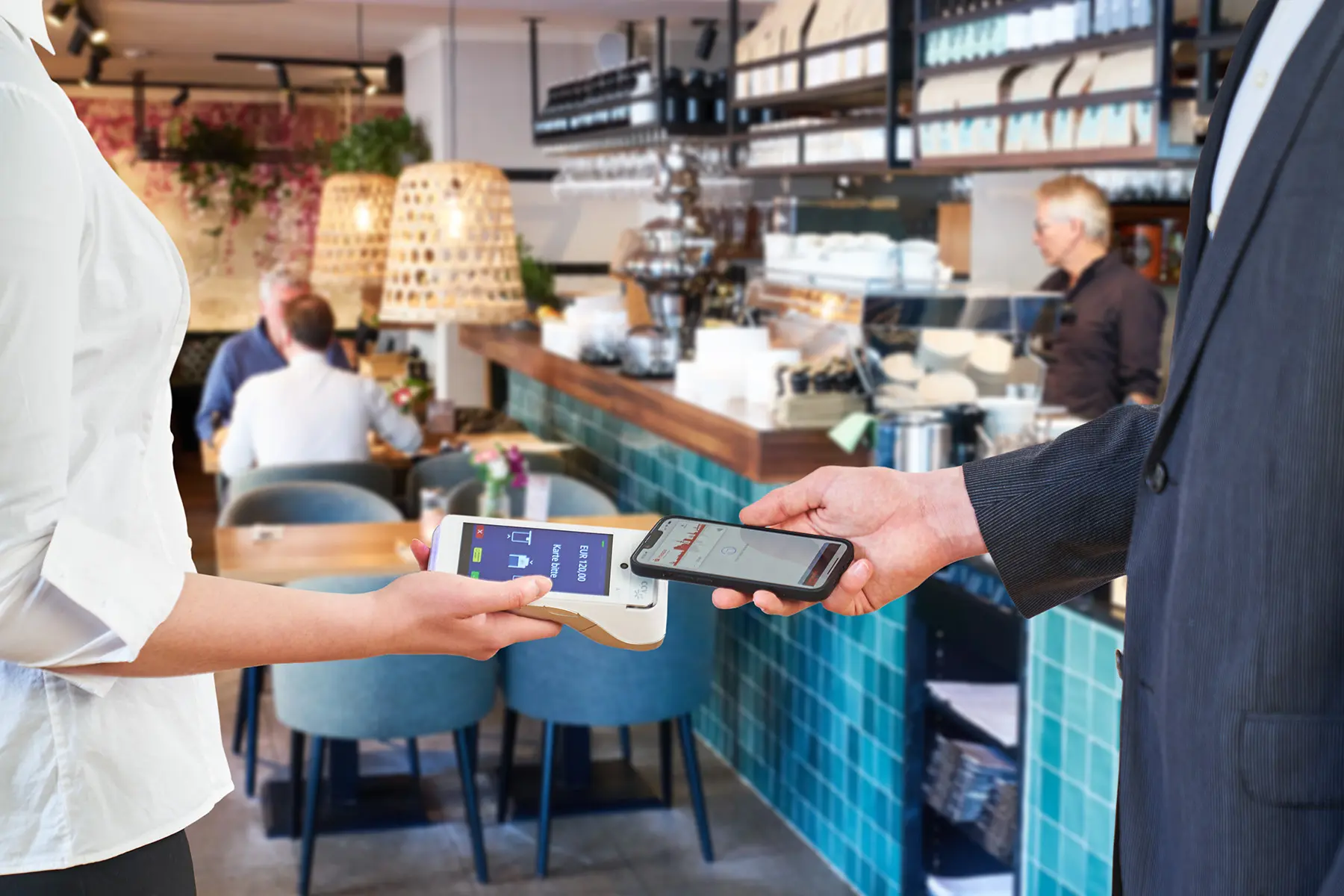 Gast bezahlt im Restaurant kontaktlos am mobilen Kartenterminal des Kellners.